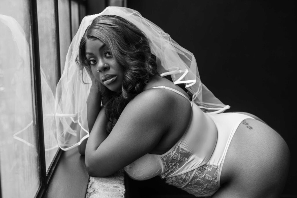 black and white bridal boudoir portrait of a woman in white lingerie and a wedding veil 